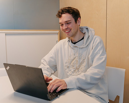 Ein Mitarbeiter arbeitet konzentriert am Laptop in einer modernen, ruhigen Umgebung – ein Symbol für effizientes, digitales Arbeiten und zeitgemäße Kommunikation.