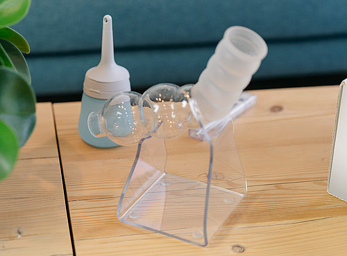 Transanales Irrigationsgerät mit transparentem Darmkatheter und Wasserreservoir, auf einem Tisch platziert.